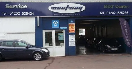 The West Way Motor Engineers workshop on Wimborne Road, the blue fascia carrying the badge, with the workshop door open and cars on the forecourt.